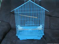 Front view of the blue bird cage showing perches and feeding cups with the brand name Lixirol visible on bottom right of the tray.