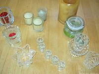 Overview photo showing 12 diverse glass candleholders and candles in red, white, green, gold, and light blue colors.