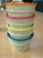 Stacked view of four plastic ice cream dishes showing the waffle cone exterior design and colored rims and lids.