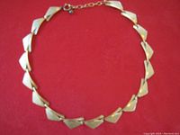Full view of the gold necklace showing the unique geometric links and clasp.