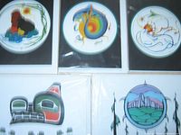 Overview of multiple Indigenous art cards laid out, showing five cards front-facing in plastic sleeves, featuring circular natural-themed designs and totem-like stylizations.