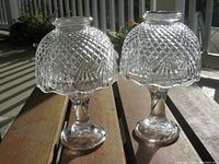 Two crystal-cut glass candle holders displayed outdoors to show their details and size.