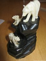 Front-side view showing three carved polar bears positioned on a multi-tiered black wooden base
