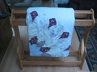 Quilt rack with commercial quilt draped over, showing partial front and side view.