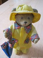 Front view of the Paddington Bear figurine showing the yellow raincoat with plaid trim, hat, and umbrella in hand.