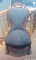 Front view of Victorian carved chair showing dark blue upholstered seat and back with carved wooden frame.