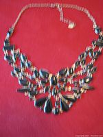 Full view of vintage Aldo necklace against red background, showing chain and pendant section.