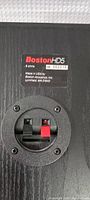 Close-up of Boston Acoustics HD5 speaker rear label and speaker terminal connections showing model, impedance, and serial number.