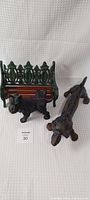 Full view of the bench with cast iron sides and wooden slats with two dog figurines in front.
