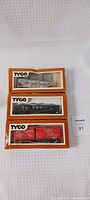 Three Tyco railroad boxcars in original boxes stacked vertically showing front and side views.