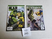 Two Hulk comic books, 'World War Hulk' and 'World War Hulk Front Line,' laid side by side on a white surface with a MaxSold tag.