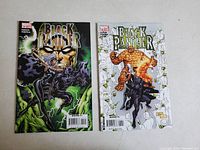 Two Marvel Black Panther comic books side by side on a grey surface