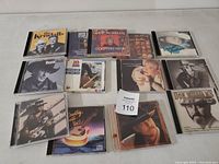 Photo of 12 country music CD cases arranged on a surface showing front covers and titles, detailing the various artists and album names.