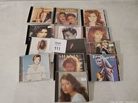 Photo showing 13 country music CDs including Shania Twain and Joan Osborne, mostly female artists in fair condition