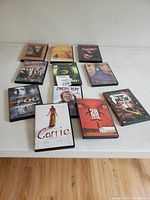 Photo showing 11 DVD cases of horror movies including zombie and werewolf themes laid out on table.