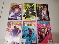 Lot of six Iron Man comics arranged in two rows of three on a flat surface. Comics include Invincible Iron Man #1, #2, #3, Adventures of Iron Man, and two others with prominent artwork of Iron Man and related characters. Comics appear in good condition with visible covers.