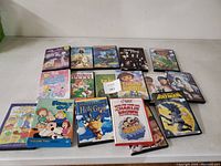 Photo showing 14 DVD cases and box sets arranged on a table featuring Family Guy, Bugs Bunny, Shrek, Batman, Dora the Explorer, and other animated titles.