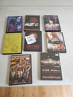 Top-down photo showing 8 music DVDs laid out on a white surface, each with distinct cover art to identify the artist and title.