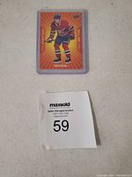 Front side of Nick Suzuki hockey card showing player in Montreal Canadiens uniform with bright orange background design.