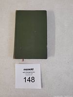 Top view of the book showing the green cover and a MaxSold number card.
