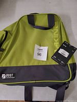 Close-up photo of the green and grey Dakine boot compartment bag with tags attached, showing brand name and boot compartment label.