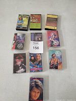 Photo of ten various music cassette tapes arranged in three rows on a white surface, showing album covers separately.