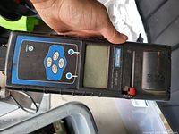 Lithonia EX-P-300 handheld battery analyzer showing control panel, LCD screen, and battery compartment.