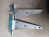 Pair of metal hinged brackets with multiple mounting holes, showing minor rust and wear