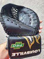 Close-up of black Louisville Pro RH catching glove showing the open pocket and stitching details, held in hand outdoors.