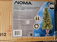 Photo of NOMA lighted Christmas tree and battery-operated wreath set box with product details and features.