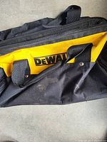 Side view of the black and yellow DeWalt tool bag showing handles and logo
