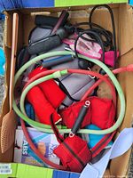 Box filled with various exercise accessories including resistance bands, gloves, wrist weights, and jump rope