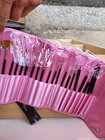 Open pink makeup brush case showing 21 various makeup brushes inside individually slotted.