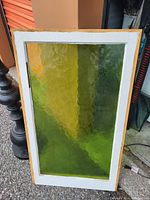 Photo of a rectangular green textured glass window panel framed in wood with white inner border