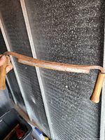 Single photo showing a vintage bow saw with rust on the metal frame and two wooden handles held up vertically.