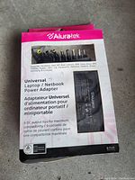 Photo of an Aluratek universal laptop/netbook power adapter in sealed retail packaging. 9 DC output tips displayed in the top section.