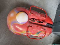 Photo of a single metal gas can painted with custom flame and bubble design with colors orange, red, yellow, white, and gray. The gas can has two metal handles and a black metal spout.