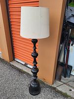 Full view of the black metal stand up lamp with white fabric lampshade.