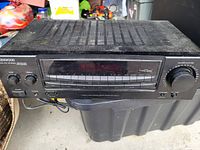 Front view of the Kenwood stereo receiver showing display, control buttons, tuning dial, and ventilation on top.