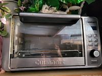 Photo of the front view of a stainless steel Cuisinart toaster oven showing the glass door, control panel with buttons and knob.