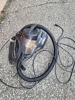Photo of entire canister vacuum cleaner showing the unit, hose, and electrical cord on an outdoor surface.