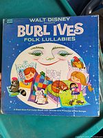 Walt Disney Presents Burl Ives Folk Lullabies record album cover showing colorful vintage artwork of a moon, children and animals with a pull-out color book included