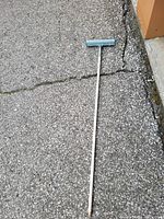 Single window cleaning squeegee on asphalt ground next to building corner