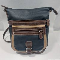 Front view of the vintage leather handbag showing the combination of black, brown, and tan leather with zipper pockets and buckle detail.
