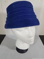 Front angled view showing royal blue velvet fabric and horizontal stitched bands on hat crown
