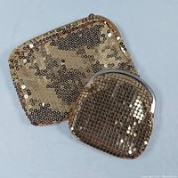 Two vintage golden sequin bags pictured on a blue background. The smaller change purse has a silver-tone metal clasp and mesh-like sequin surface. The larger cosmetic bag has a zipper closure and dense golden sequins.