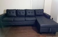 Full view of black leather sectional sofa with chaise on right