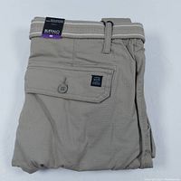 Folded tan cargo shorts with buttoned back flap pocket, belt loops and attached woven belt