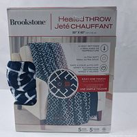 Photo of the Brookstone heated throw package showing product image, size (50" x 60"), and key features: 4 heat settings, ultra-soft fabric, safe 4-hour auto-off, built-in remote control.
