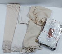Lot contents shown: three vintage half-slips made of nylon and poly/cotton Eaton fabric in cream and white colors with lace hems, plus package of unused vintage seamless nylon hosiery from Italy.